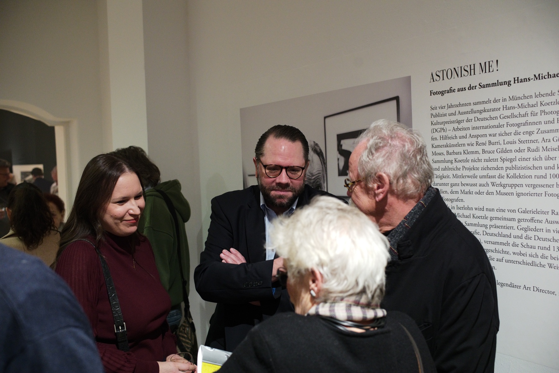 Gäste im Gespräch vor dem Einführungstext der Ausstellung Astonish me